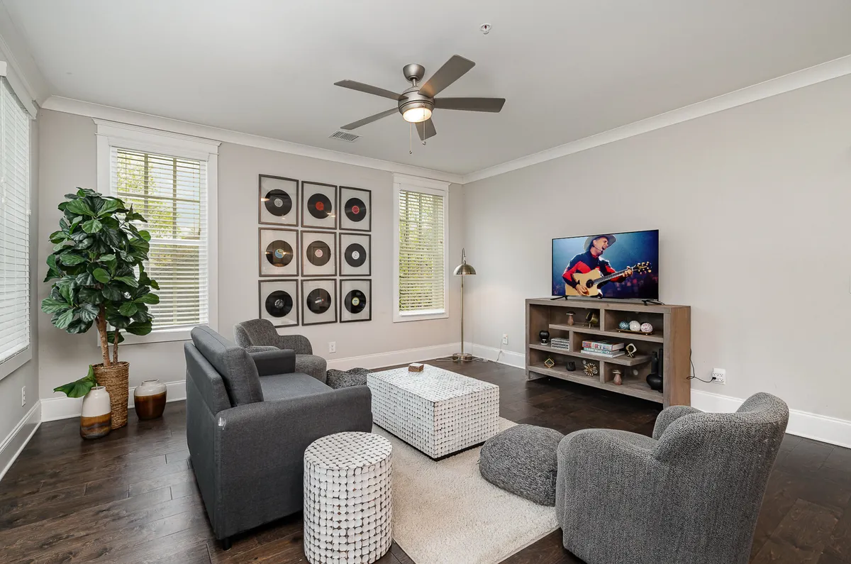 The image showcases a stylish, light-filled living room with a cozy sofa seating area, a wall-mounted television, and an eye-catching record display. The space is designed for relaxation and entertaining, exuding a blend of modern comfort and Nashville-inspired charm.