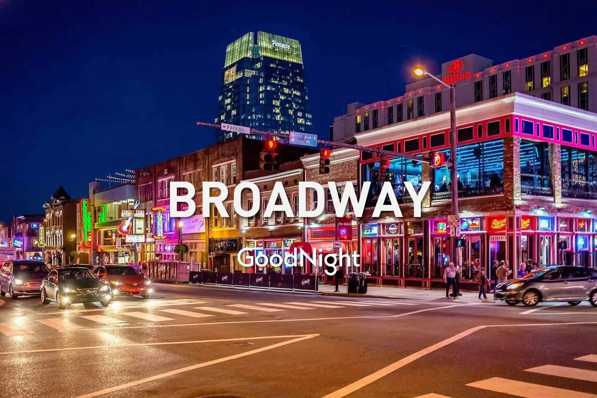 A vibrant city scene at night featuring bright neon signs, a bustling intersection, and prominent nightlife venues with the Nashville skyline in the background. Crowds gather outside, reflecting the city's energetic social atmosphere.